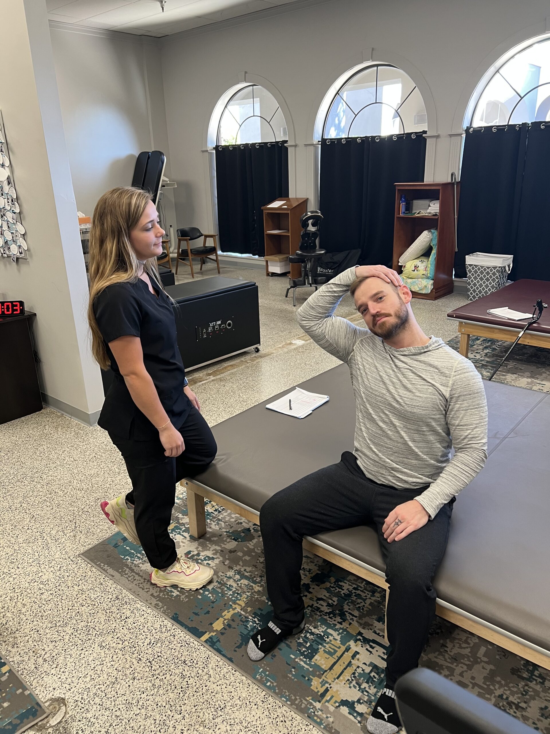 Patient doing guided neck stretch exercise with chiropractor